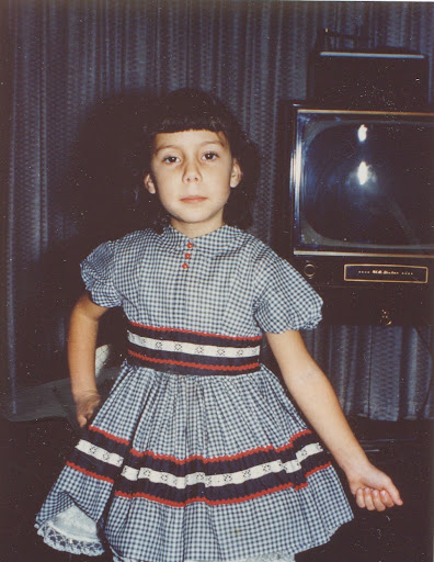 a young girl posing seriously in front of a TV set